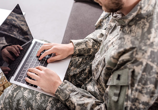 Military student works on a laptop.